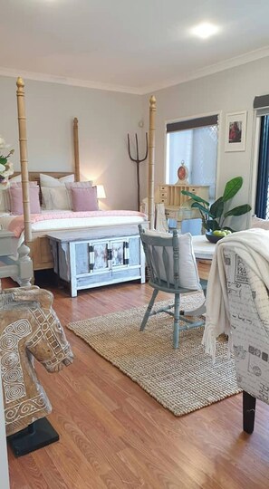A bedroom with a four-poster bed, a desk, a chair, a small table, and a potted plant. - Room-stylish Studio in Reedy Creek (Gold Coast)