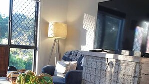 Una sala de estar con sofá, mesa de centro, lámpara y televisor.