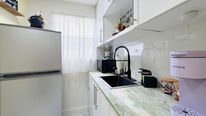 Eine Küche mit Kühlschrank, Mikrowelle, Spüle und einer Keurig-Kaffeemaschine.