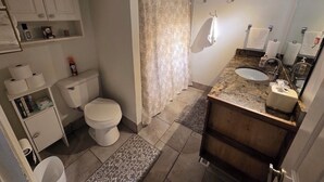 Un baño con inodoro, cortina de ducha, lavabo y barra para toallas.