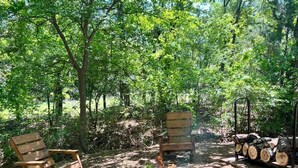 A campsite with a fire pit, wooden benches, and a log storage area. - Arbuckle Lake Hideaway (Sulphur)