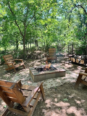 A campsite with a fire pit, wooden benches, and a log storage area. - Arbuckle Lake Hideaway: Deer Views, Boat Parking in Sulphur (Sulphur)