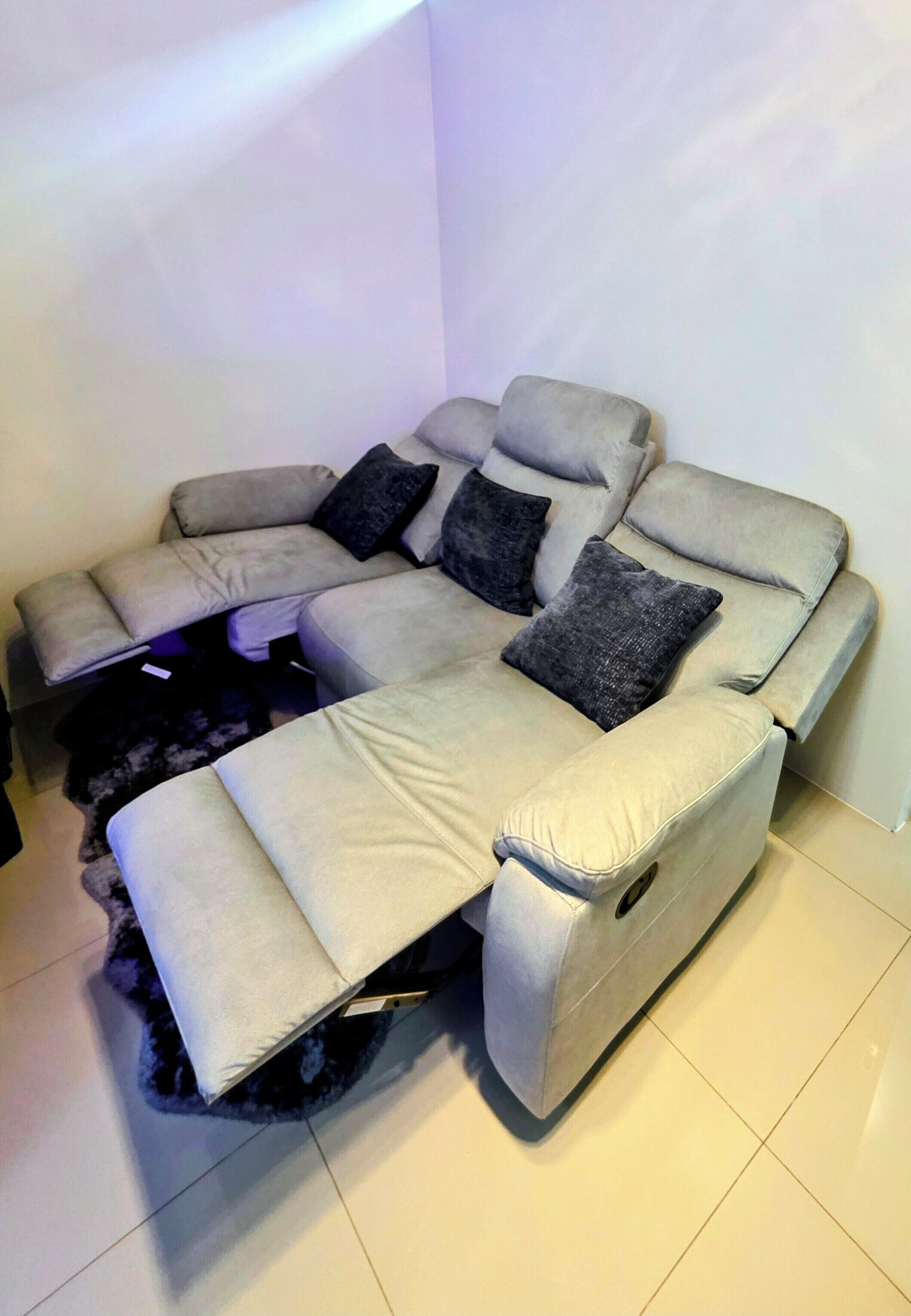 A sectional sofa with a footrest and a remote control on the armrest.