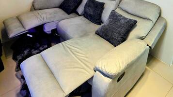 A sectional sofa with a footrest and a remote control on the armrest.