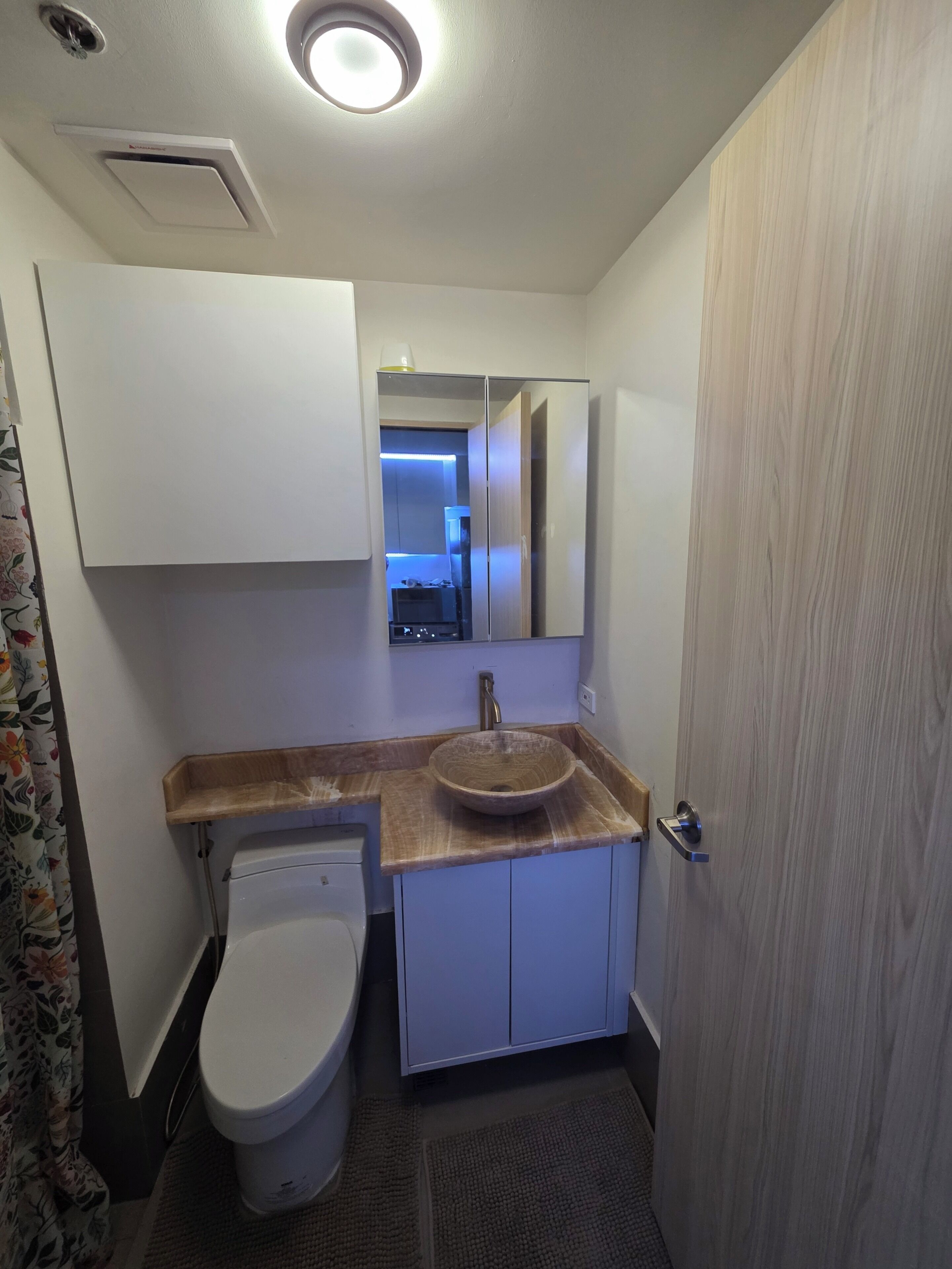 A bathroom with a toilet, sink, and cabinet.