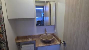 A bathroom with a toilet, sink, and cabinet.