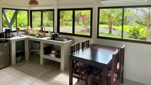 Cucina con piano cottura a gas, lavello e zona pranzo con sedie.