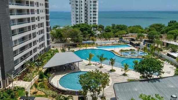 A hotel with multiple swimming pools, a covered seating area, and a view of the ocean. - Luxury Apartment Suite in Santa Marta | Ocean View (Santa Marta)