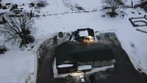 Luchtbeeld van een gebouw met een ruime garage, een oprit en een besneeuwd landschap.