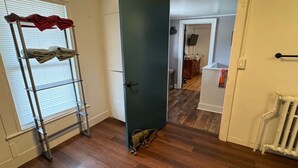 Een gang met een metalen ladder, een deur en een radiator.