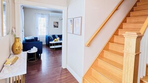 Amplia sala de estar con una escalera de madera, una mesa de comedor y un sofá.