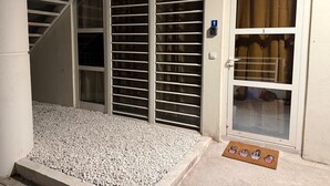 Un hall d’entrée d’habitation avec un escalier, une porte-fenêtre coulissante et un paillasson.