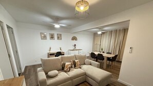 Un salon moderne avec un canapé d’angle, une table basse en bois et un coin repas comprenant une table et des chaises.