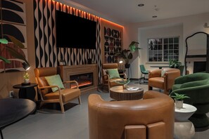 Uma sala de estar moderna com sofás de couro, uma lareira e uma televisão grande fixada na parede.