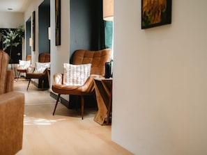 Ein modernes Interieur mit Ledersesseln, einem Holztisch und einer Wandleuchte.