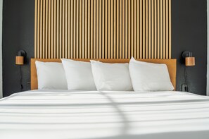 Uma cama com lençóis brancos e cabeceira de madeira.