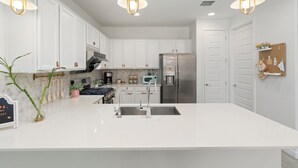 A modern kitchen with white cabinets, stainless steel appliances, and pendant lighting. - Game Day Stay - Community Pool Access + Walk to Stadium + Close to Westgate (Glendale)