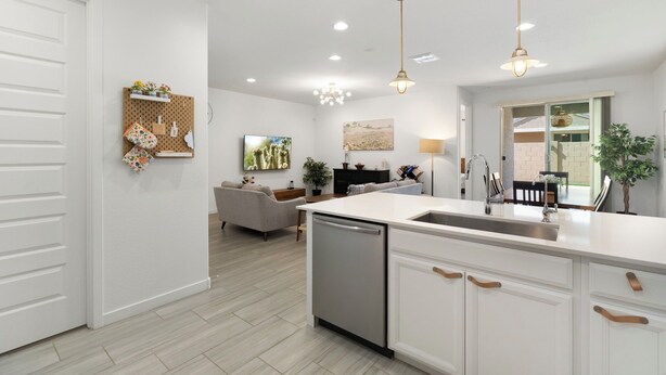 A modern kitchen with a dishwasher, white cabinetry, pendant lighting, and a dining area with a table and chairs. - Game Day Stay - Community Pool Access + Walk to Stadium + Close to Westgate (Glendale)
