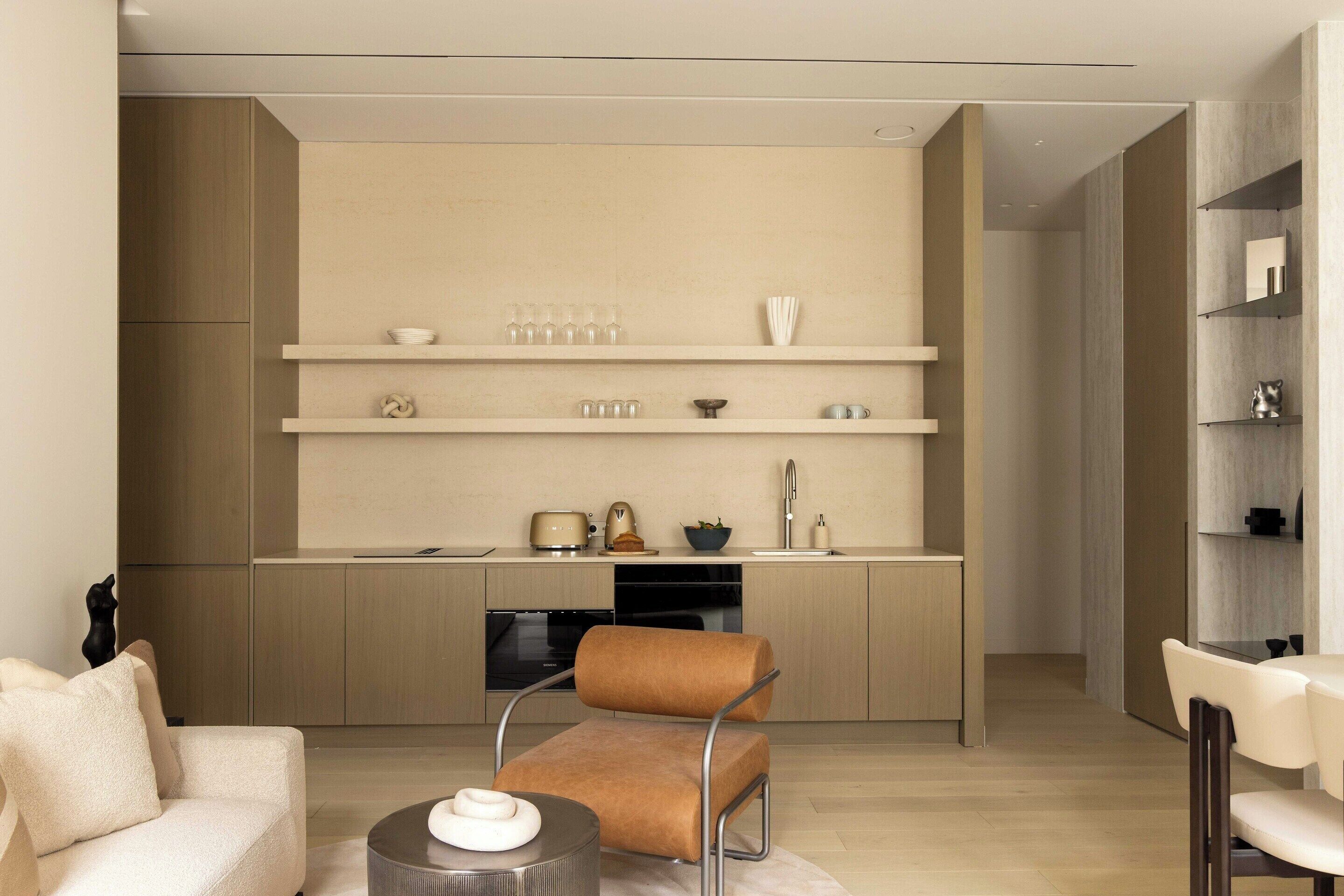 A modern kitchen with built-in appliances, a dining area with a sofa and chairs, and a minimalist design.