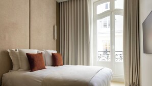 Hotellihuone, jossa on suuri sänky, ikkuna, jossa on verhot, ja näkymä ulos.
