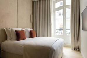 Ein Hotelzimmer mit einem großen Bett, einem Fenster mit Vorhängen und Blick nach außen.