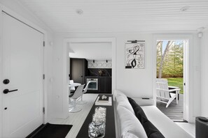 Ein modernes Interieur mit einer weißen Tür, einer Küchenzeile mit Esstisch und Blick durch eine Glastür auf eine Terrassenanlage.