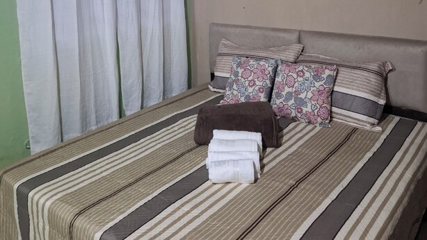 Ein Bett mit gestreifter Bettwäsche, einem Kopfteil und dekorativen Kissen.