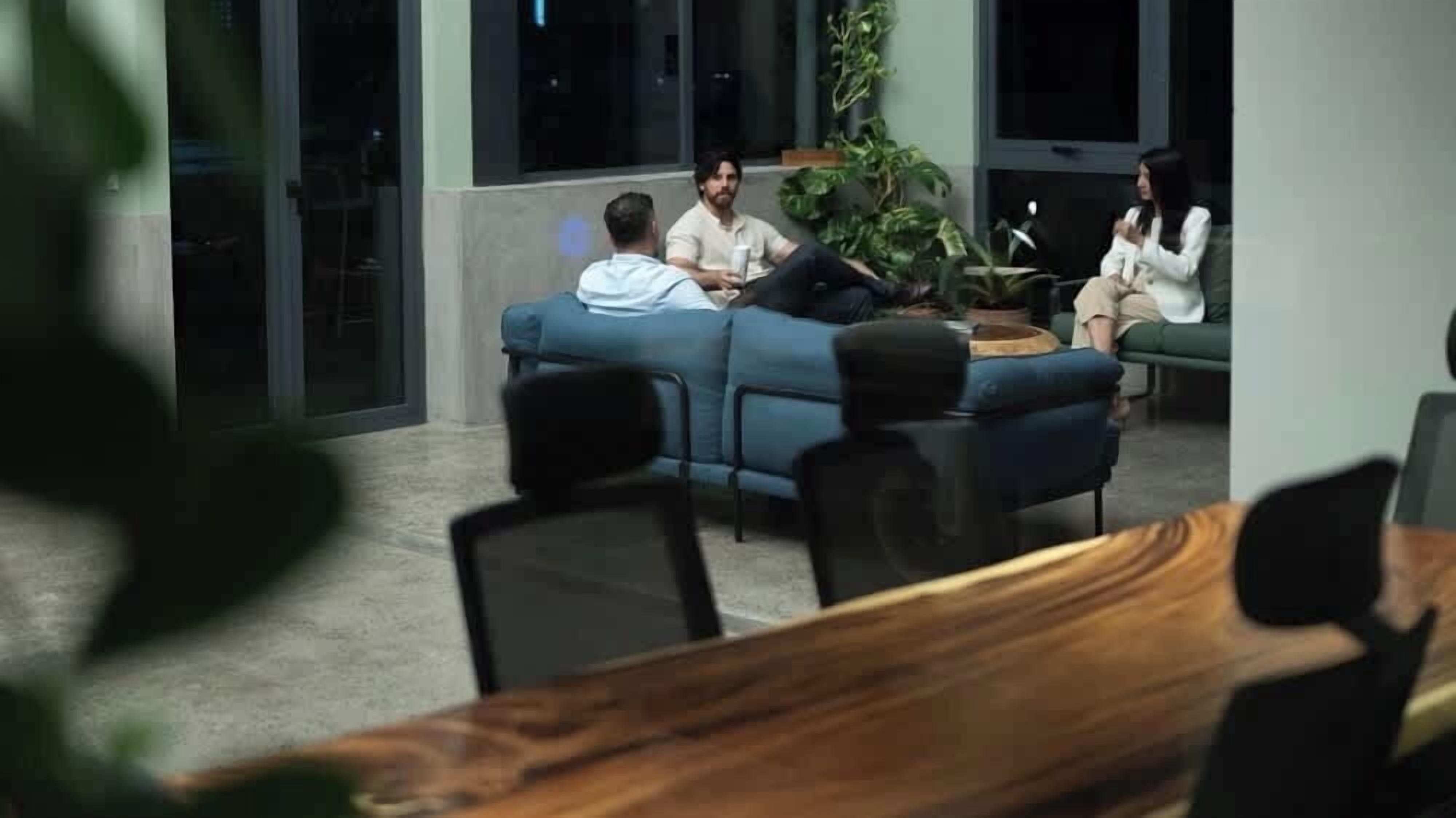 A room with a blue sofa, a wooden table, and a glass door leading to another space.