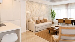 A modern living room with a sofa, coffee table, and dining area. - Lovely & Comfy I - Checkinhome (Monte Estoril)