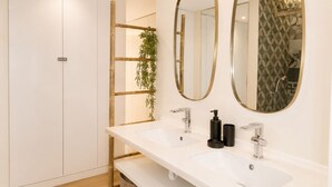 Un baño moderno con dos lavamanos, un espejo y una ducha.