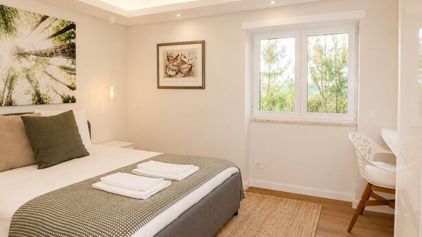Un dormitorio con cama, ventana, una silla y obras de arte en las paredes.