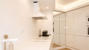 Una cocina moderna con armarios blancos, una campana extractora de acero inoxidable y una cafetera sobre la encimera.
