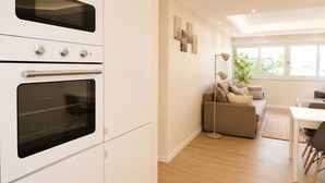 Una cocina moderna con hornos empotrados y un comedor con sofá y mesa.
