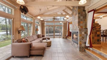A spacious living room with a large sectional sofa, a fireplace, and large windows offering a view of the outdoors.