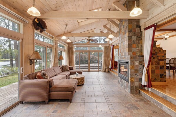 Una habitación amplia con un sofá grande tipo seccional, una chimenea y ventanas grandes.