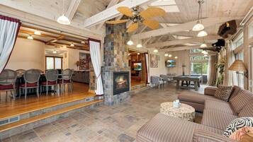 A spacious living area with a fireplace, comfortable seating, and a high ceiling with exposed beams.