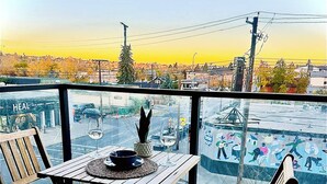 Ein Holztisch und Stühle auf einem Balkon mit Blick auf die Stadt.