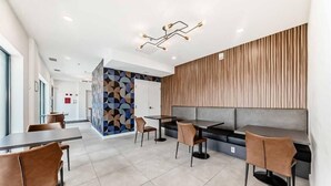 Ein modernes Restaurant mit einem geometrischen Wandmuster, einer Holzvertäfelung und einer Sitzgruppe mit Tischen und Stühlen.