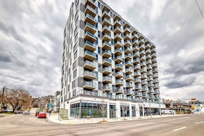 A modern high-rise building with multiple balconies, a glass facade, and a commercial ground floor. - Downtown Condo, Stylish & Comfy (Calgary)