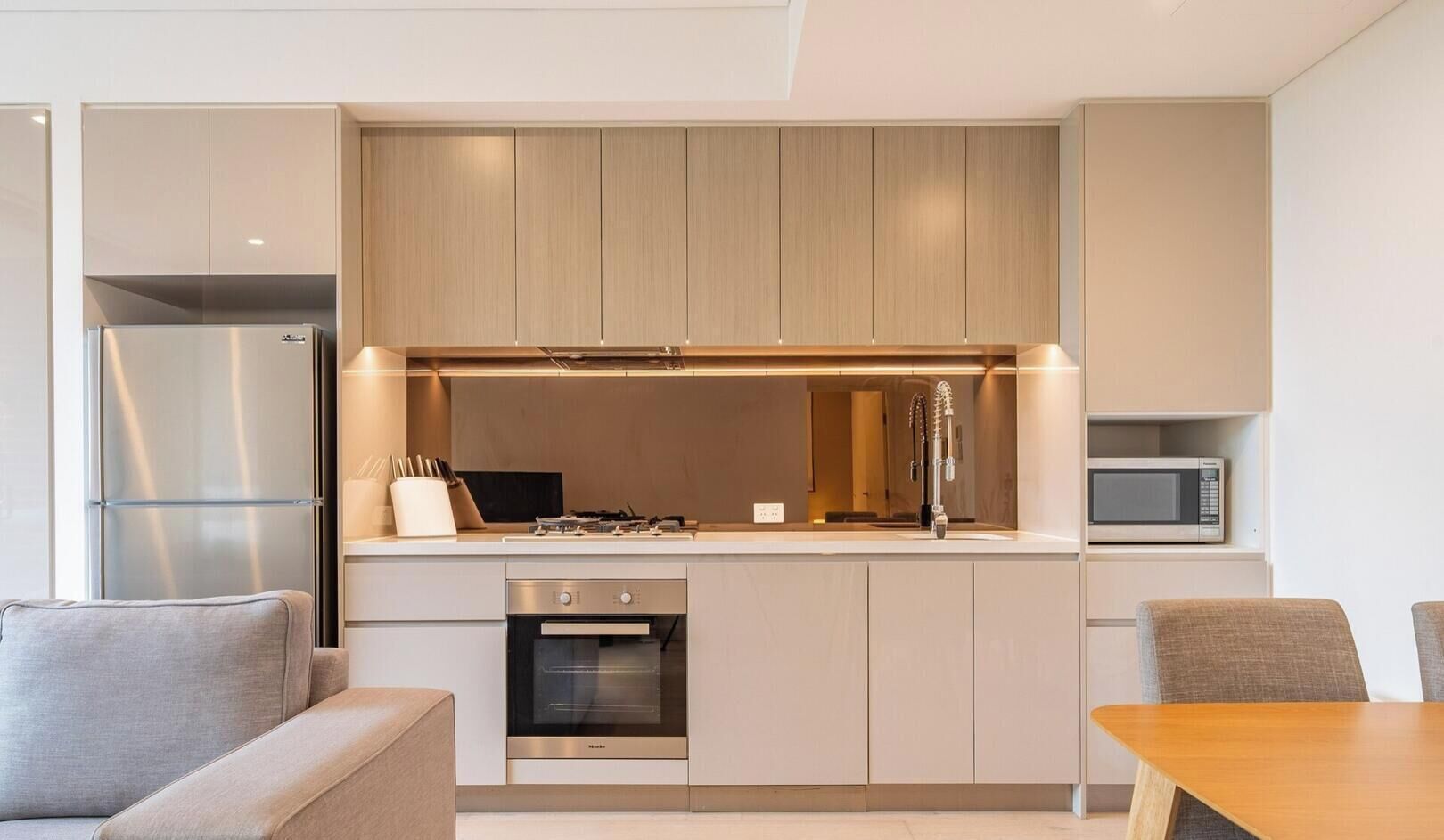 A modern kitchen with built-in appliances, a dining area with a table and chairs, and a sofa.