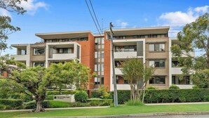 A multi-story residential building with balconies, a brick facade, and a sign indicating 'One Victoria Park.' - KozyGuru | Roseville | Modern Leafy Retreat (Roseville)