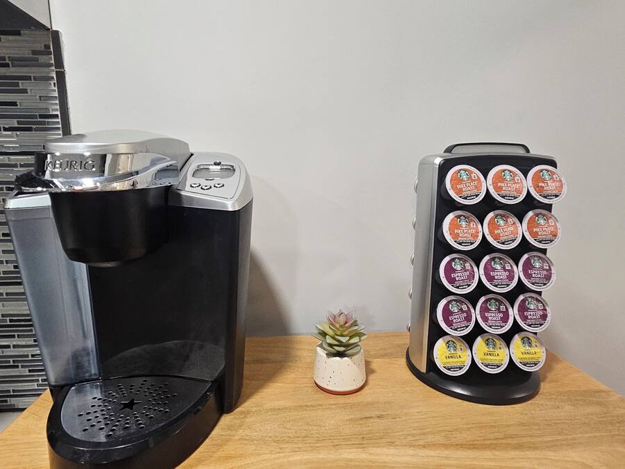 A coffee maker and a coffee pod holder on a wooden table.