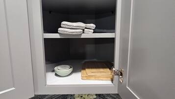 Una cocina con un lavamanos, una tabla de cortar, un bol y una botella de detergente.