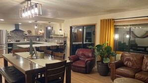 Een moderne woonkamer met een eethoek, lederen meubels en een groot raam met gordijnen.
