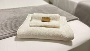 Una cama bien hecha con una toalla blanca doblada y una etiqueta que dice 'PHYTOORVAS'.