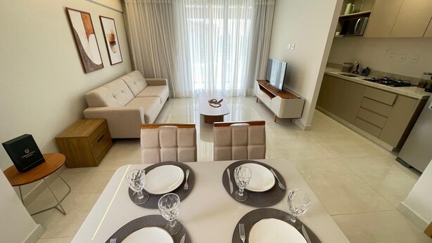 Una sala de estar moderna con sofá, comedor, zona de cocina y televisor.