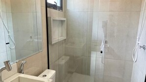Un baño moderno con ducha, inodoro y lavamanos.