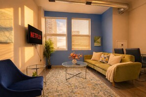 A living room with a sofa, a coffee table, and a TV mounted on the wall. - South Loop 2BR Oasis w/ Patio & Gym Near McCormick Place and Soldier Field (Chicago)