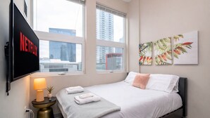 Ein modernes Hotelzimmer mit einem Bett, einem an der Wand montierten Fernseher und Kunstwerken an der Wand.