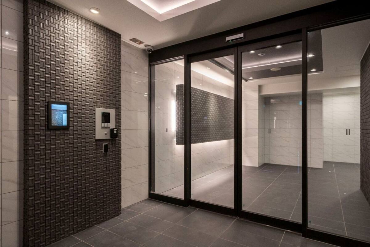 Un interior moderno con una pared estampada, un acceso por puerta de cristal y suelo de baldosas.